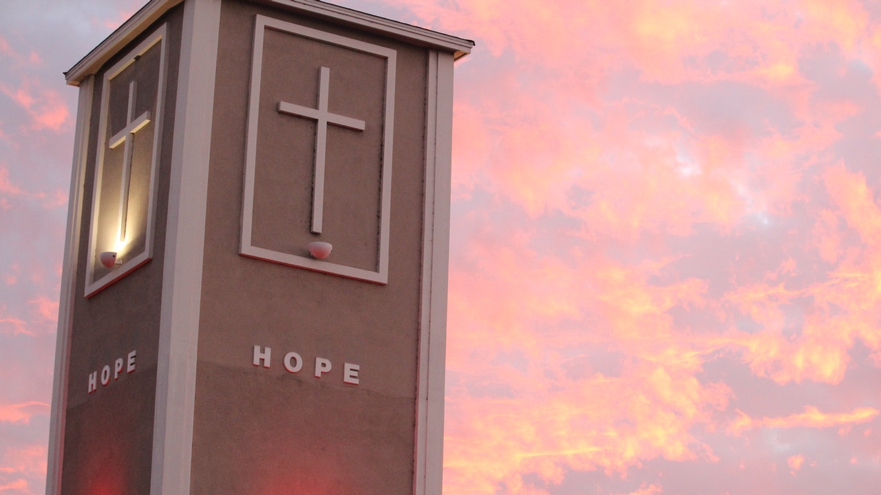 A building structure against the sun set, with the cross engraved on it and the word Hope written under the cross.