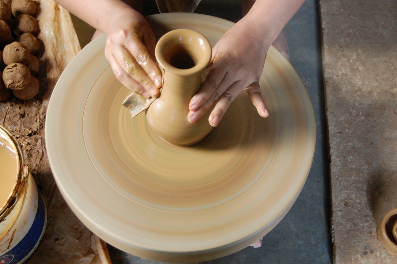 Hands creating a clay vessel on a Potters wheel