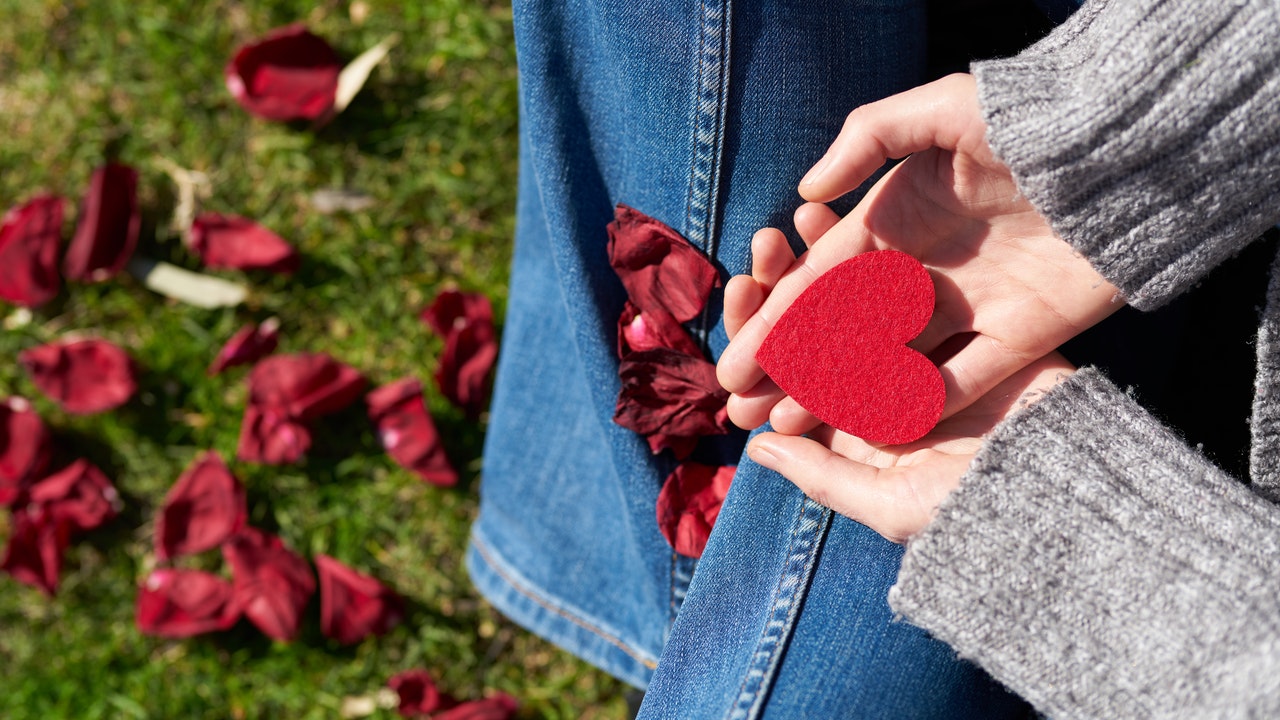 A person holding a red heart paper cut out.
