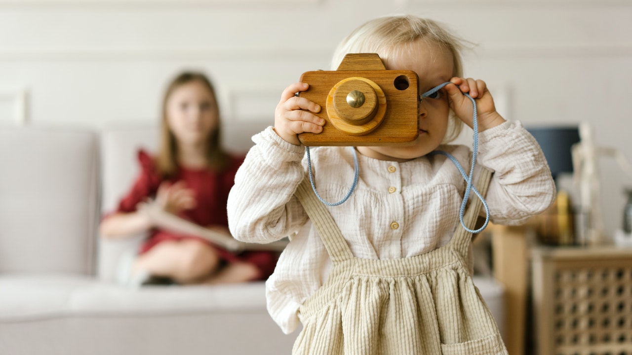 A toddler looking through a wooden camera lens