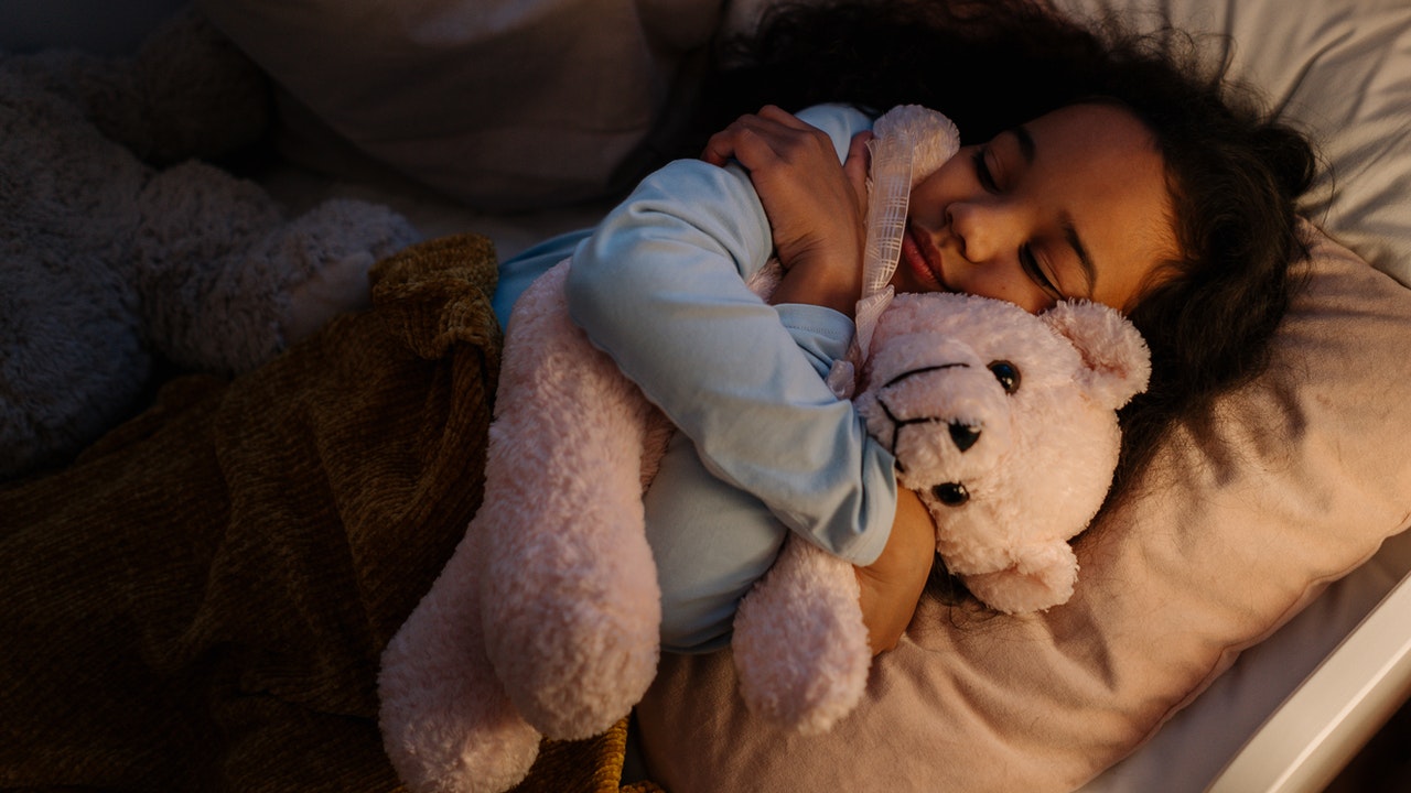 An Adorable Girl Hugging her Teddy While Sleeping