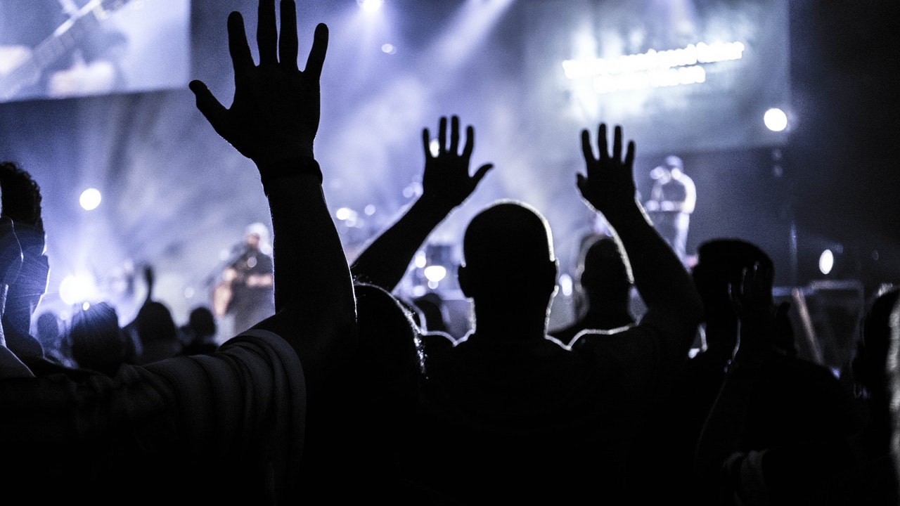 Silhouette of a group of people raising their hands in worship to God
