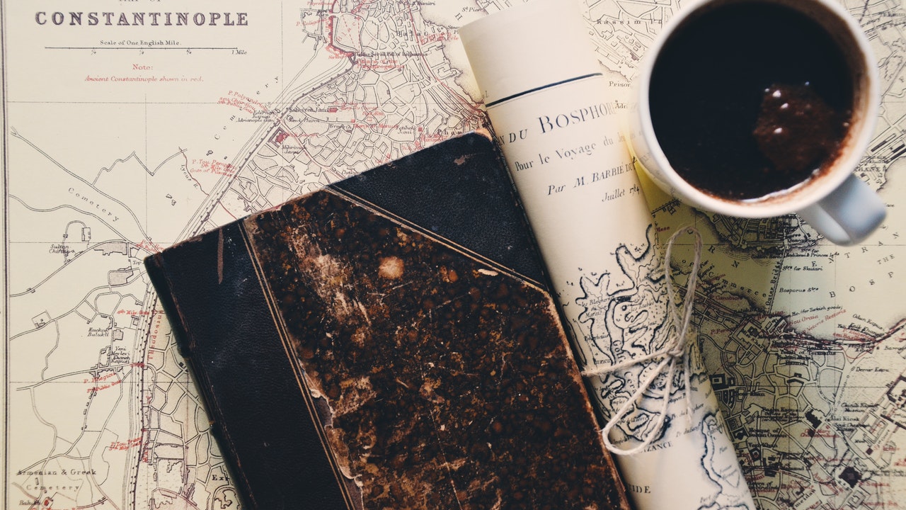book and a cup of coffee on a map