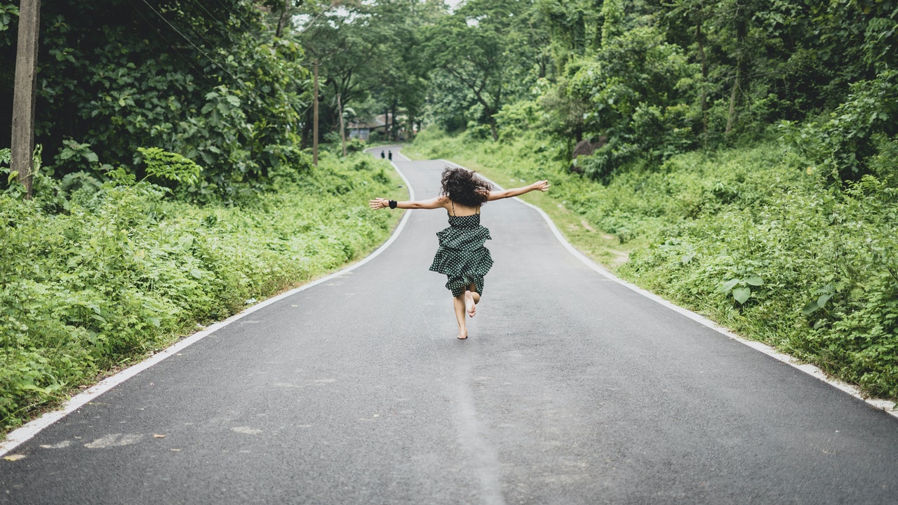 Woman running to freedom on an open road.