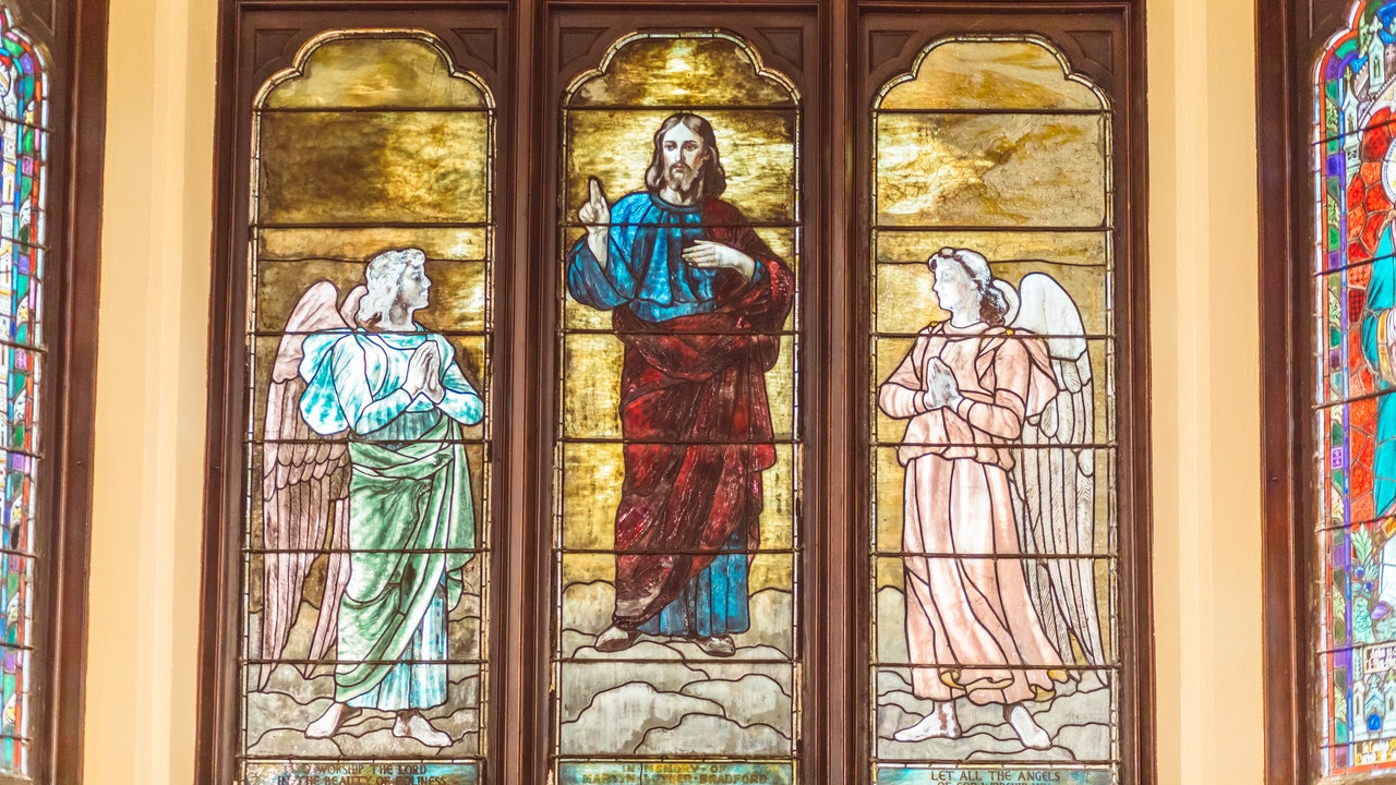 Stained Glass painting of Jesus in the middle of two Angels.