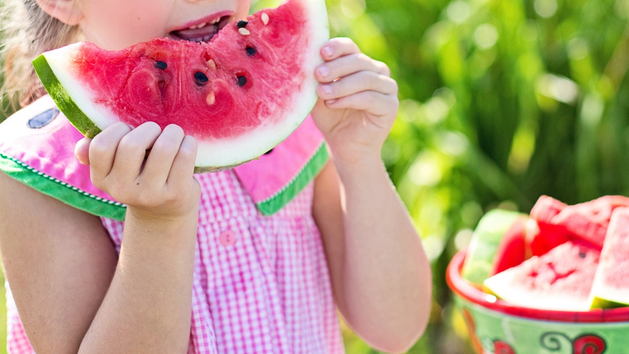 Girl eating sliced watermelon.