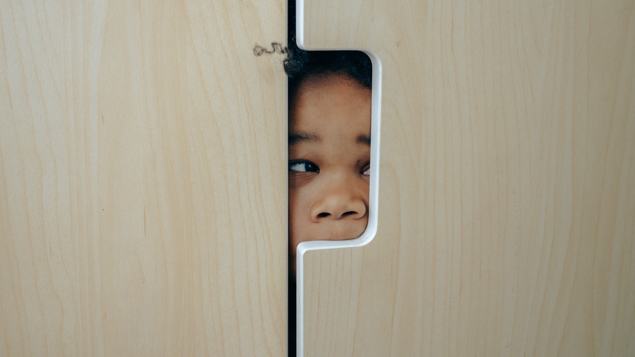 Playful Black little girl hiding in a closet