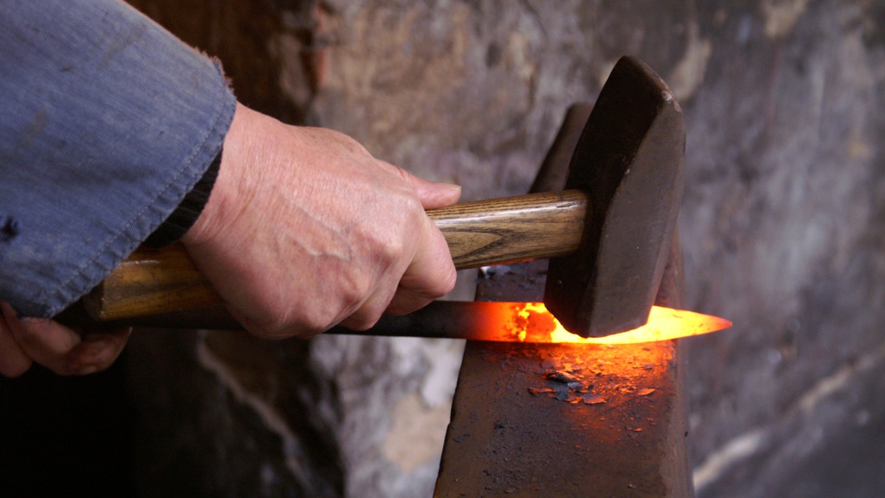 A person holding and forging metal