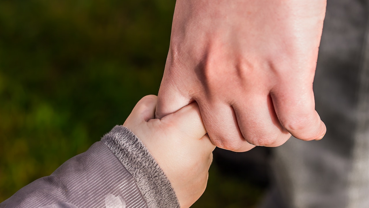 A child holding the hands of an adult.