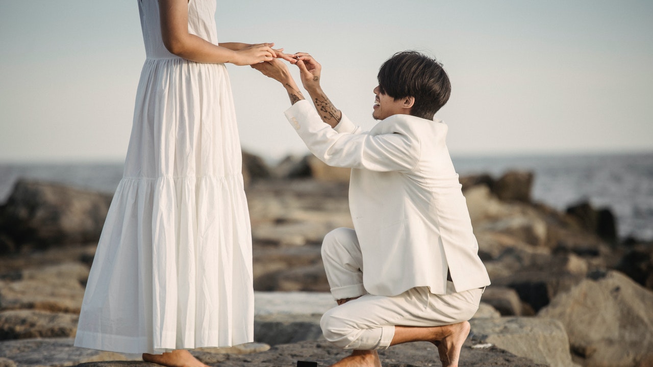 A man kneeling low to propose to a woman.