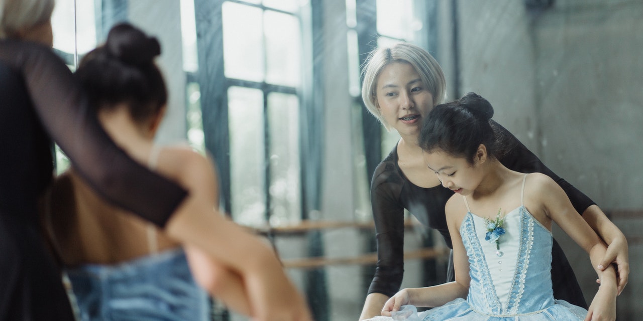 Asian teacher training a young girl in ballet.